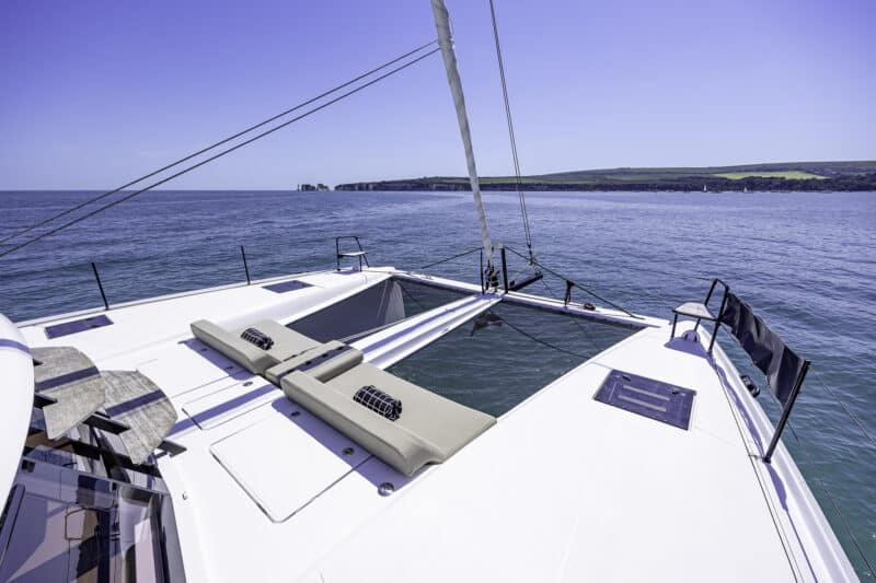 Luxury bow seating and sunbathing area aboard Seven Days catamaran with panoramic sea views towards Old Harry Rocks on the Jurassic Coast.