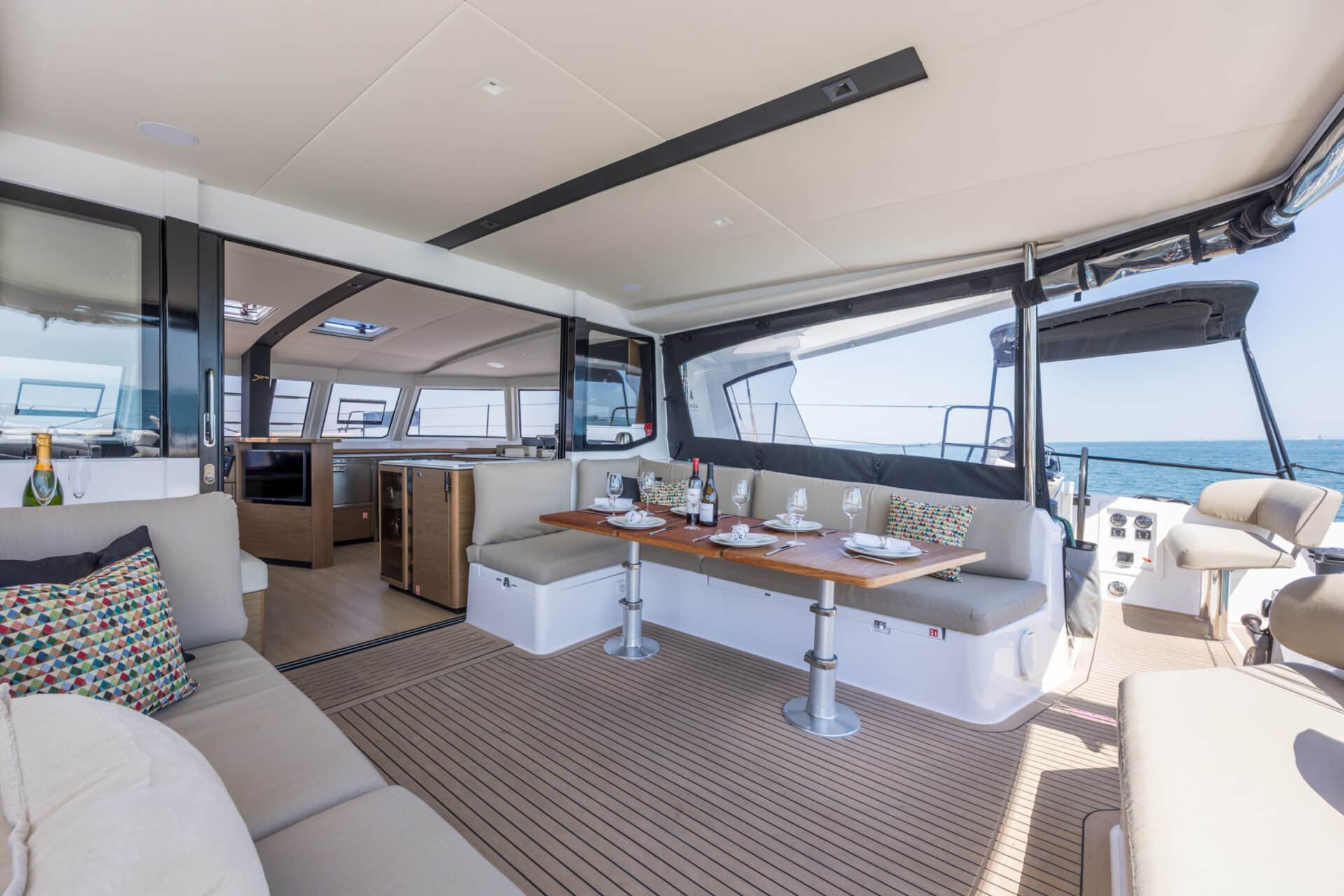Open-plan indoor and outdoor living space aboard the Seven Days luxury catamaran, featuring panoramic sea views, flexible seating and alfresco dining.